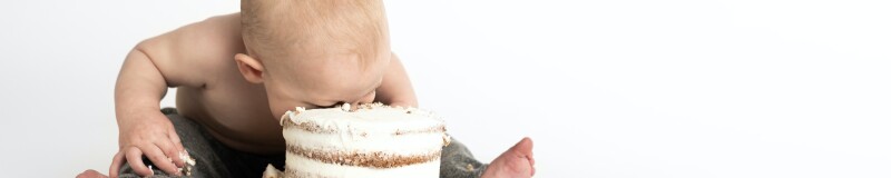 Baby sitting on the floor with its face in a cake