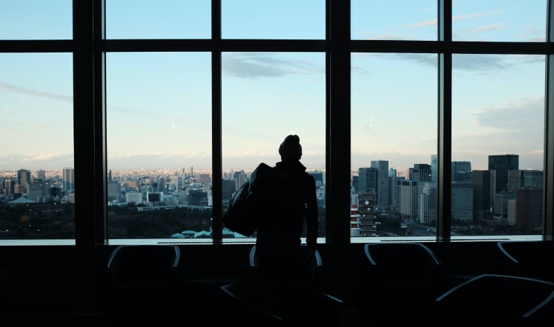 Person standing in front of a large window overlooking a city scape