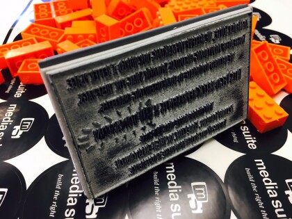 A sheet of Media Suite stickers covered with orange lego bricks and a stamp on its side