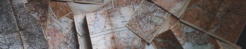 Aerial shot of several old maps spread out over a surface
