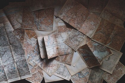 Aerial shot of several old maps spread out over a surface