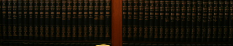 Book open on a desk with shelved books behind the desk