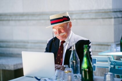 Older gentleman with moustache using laptop outdoors
