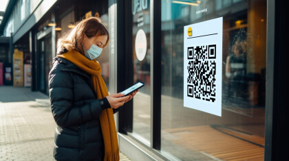 Woman looking at her phone while scanning a QR code on a shop window