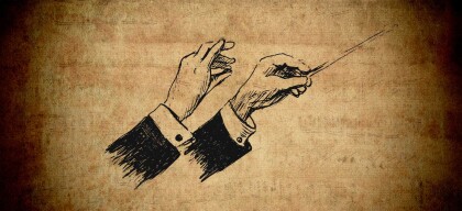 Conductor’s hands holding baton, white shirt visible