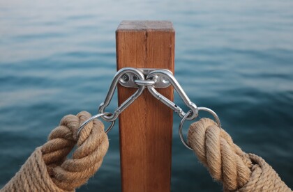 Two thick ropes clipped to a post, water in background