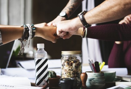 five people fist-bumping over a table