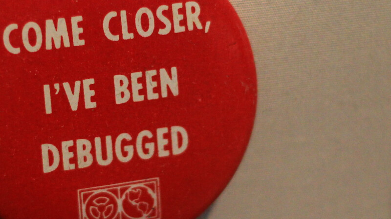 Close up image of a badge that says "Come closer, I've been debugged"
