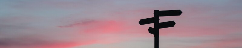 Silhouette of a sign post against a sunset