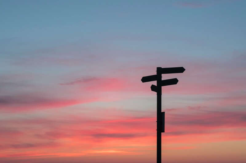 Silhouette of a sign post against a sunset
