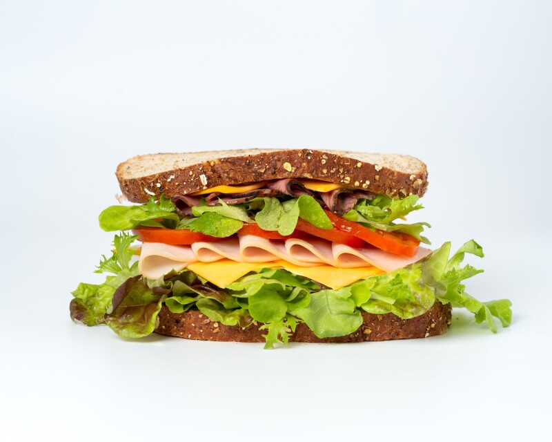 Sandwich on brown bread with lettuce, cheese, ham and tomato