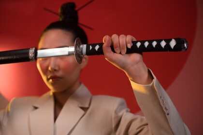 Woman in beige suit holding a samurai sword