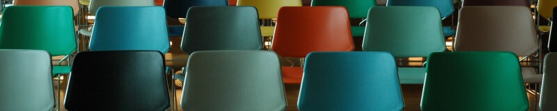 A lecture hall of empty, coloured chairs