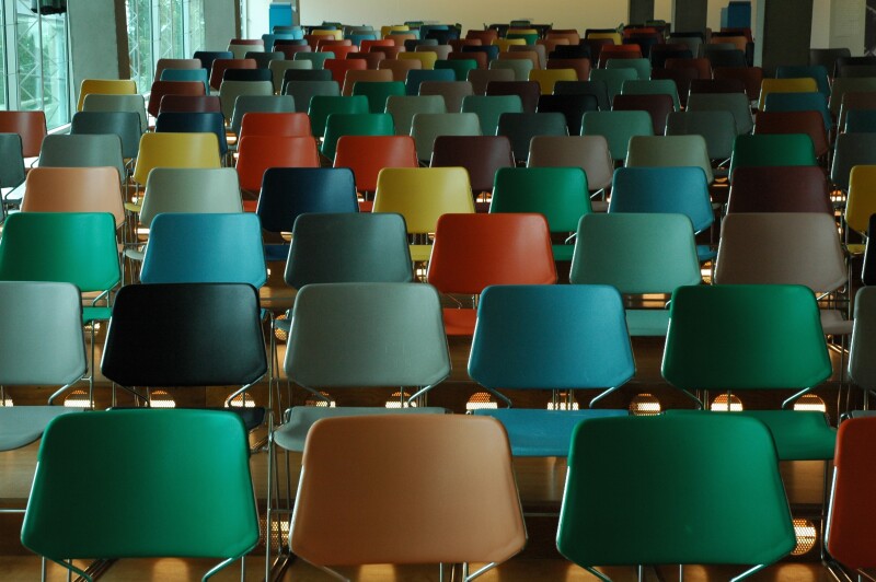A lecture hall of empty, coloured chairs
