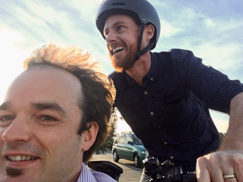 A person wearing a helmet riding a bike and another person's face in front of him