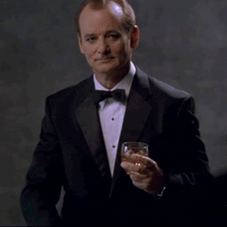Gif of Bill Murray in a tuxedo holding a glass of whisky in his right hand, and raising his left hand and pointing his fingers