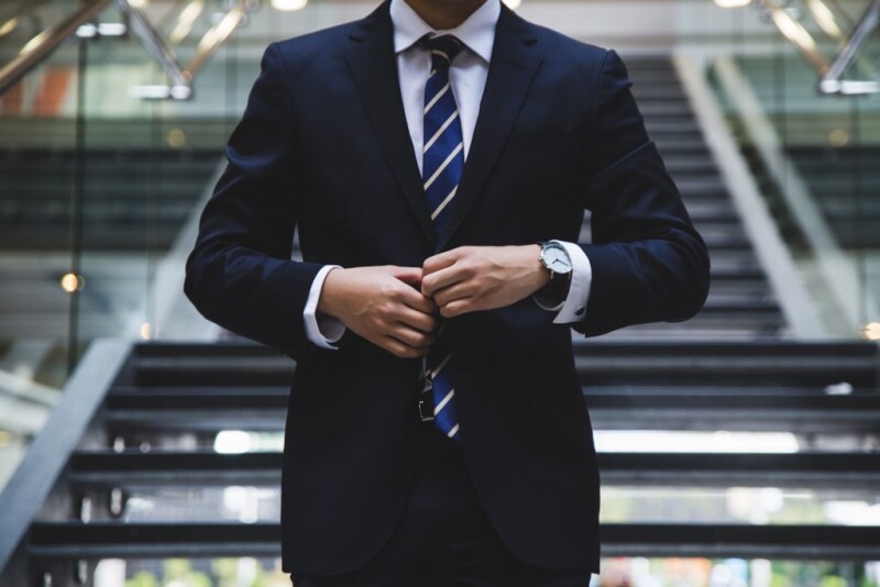 Business person adjusts suit while standing on staircase