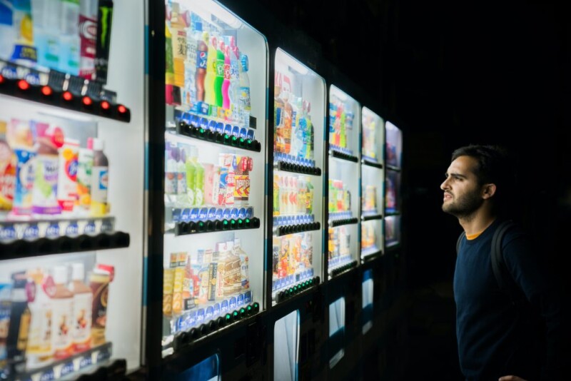 A person standing in front of multiple vending machines in a black room