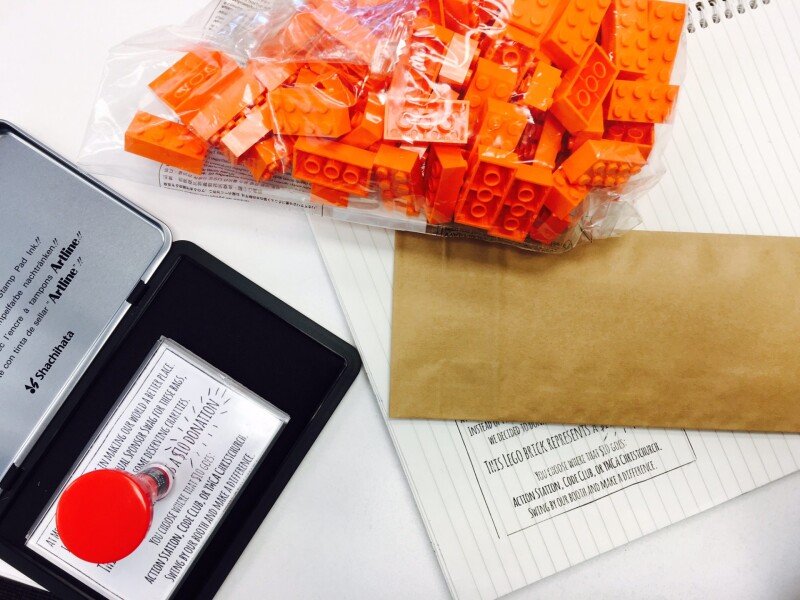 Stamp on an open inkpad. A bag of orange lego, a brown envelope.