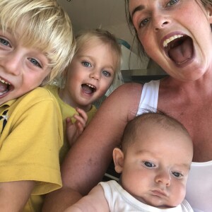 Happy selfie of mum holding baby with two happy kids to her right