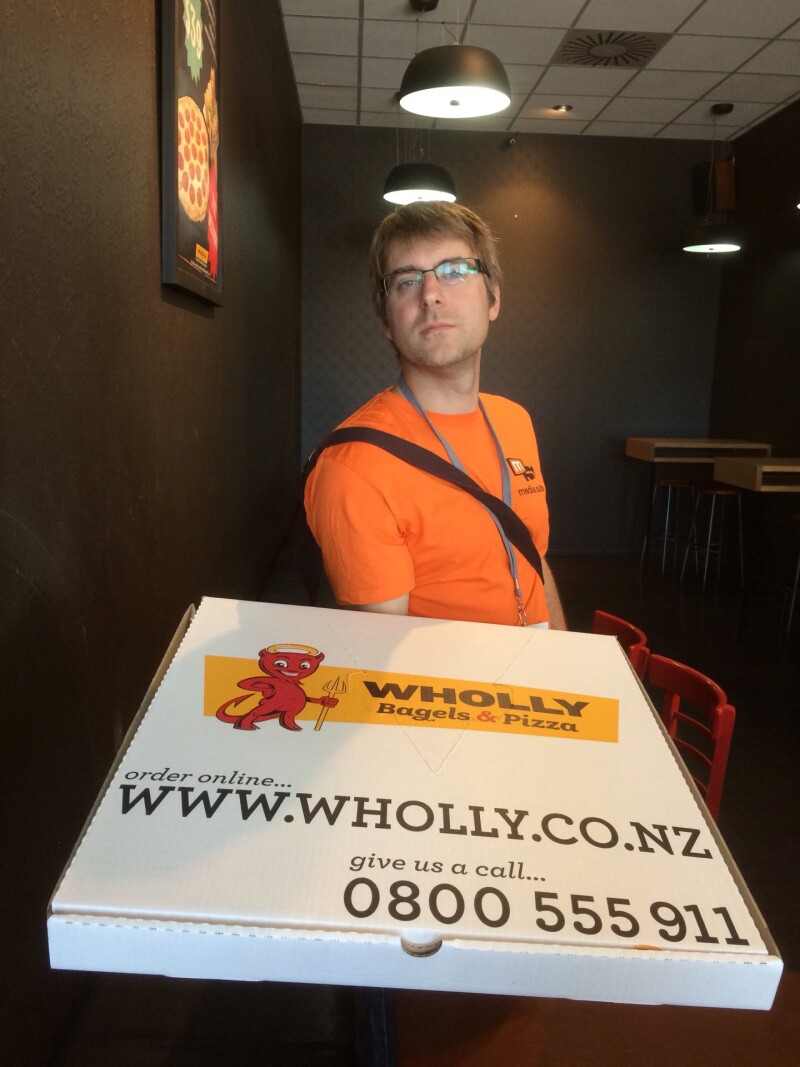 Queenstown Dev Jonathan holding a giant pizza box from Wholly Bagels & Pizza