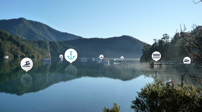 Image of a calm bay and moored boats in the Marlborough Sounds. Icons are overlayed indicating swimming, boat ramp, bouy, anchor.
