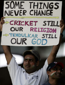 Man holding a sign above his head which says "Some things never change: Cricket still our religion; Tendulkar still our God"