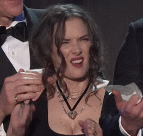 Gif of Winona Ryder at an awards ceremony; she has her hands balled in fists and pumps them in front of her while mouthing F**** yeah