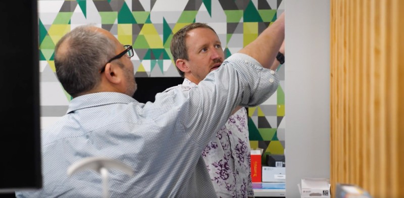 Two people drawing on a white board in discussion