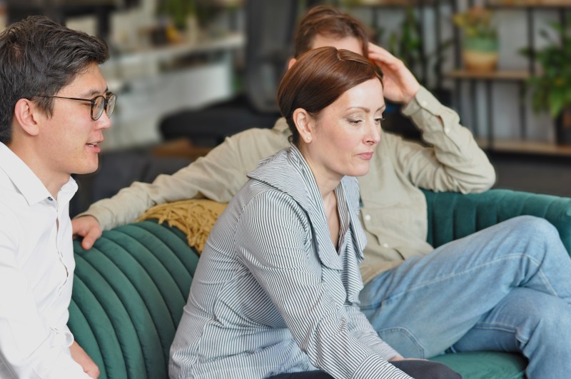 Three people sitting on a green couch in discussion