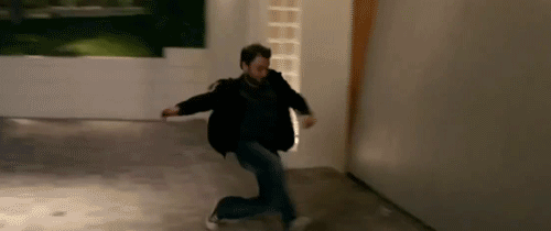 Gif of man running in a room, sliding on the floor and hitting the wall